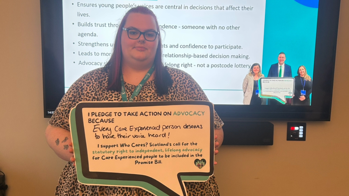 Emma holding a sign about care-experienced people