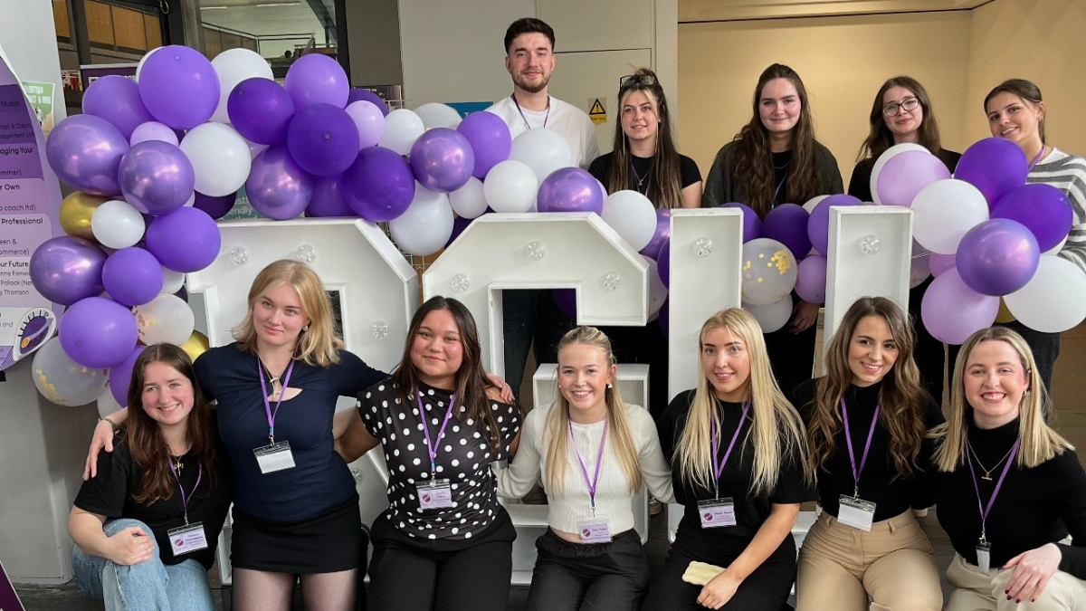 Events Management students posing in front of a big RGU sign